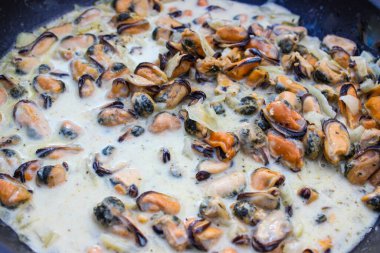 Kızartma tavasında krema soslu midyeler.