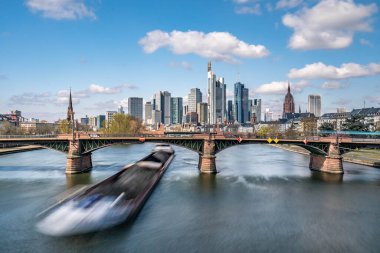 Frankfurt, Almanya - 31 Mart 2020: Frankfurt ufuk çizgisi manzaralı bir kargo gemisi ignas bubis köprüsünün altından geçiyor