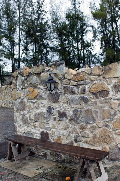 Taş duvar ve ahşap bir bank oldukça eski görünüyor.