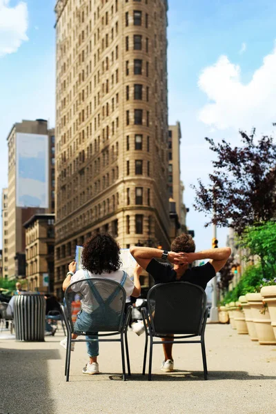 Tourists sit on chairs in a Park