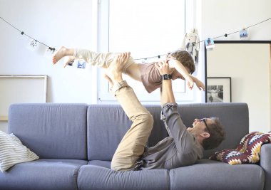 Baba ve küçük oğlu kanepede oynuyorlar.