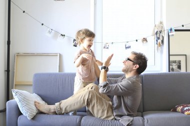 Baba ve küçük oğlu kanepede oynuyorlar.