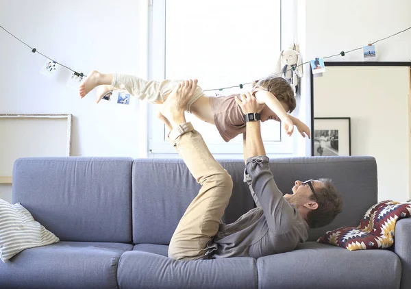 Baba ve küçük oğlu kanepede oynuyorlar.