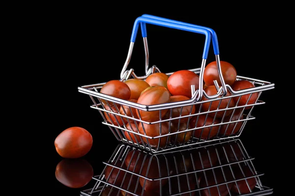 Siyah arka planda kiraz domatesli tutacakları olan minyatür market sepeti.