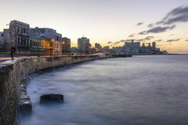 Havana 'da Malecon Denizi' nin üzerinde binalar ve bulutlarla gün batımı