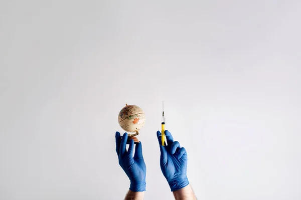 Symbol of health insurance on a global scale. Hands in medical gloves with a syringe on a white background with copy space. Global pandemic. Viral infection vaccination
