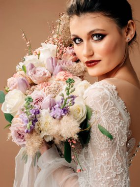 Düğün konsepti. Gelinlikli güzel gelinin stüdyo portresi ve gelin buketi.. 