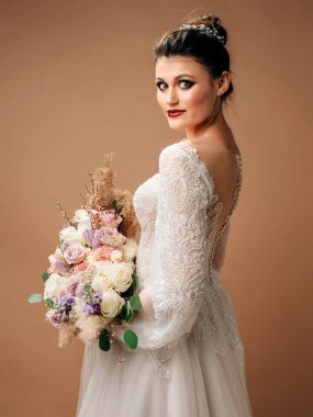 Gelinlik içinde güzel esmer gelin ve büyük gelin buketi yakın plan. Düğün konsepti. Gelin modası.