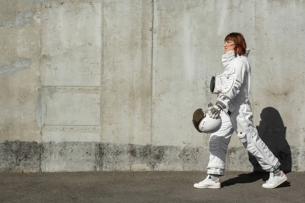 灰色の壁の背景にヘルメットのない美しい女の子の宇宙飛行士。幻想的な宇宙服. — ストック写真