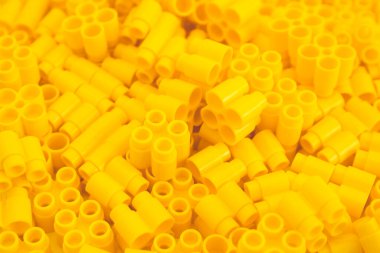 Sarı renkli plastik tuğlalar ve oyuncağın detayları. Sarı arkaplan.