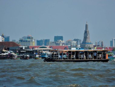 BANGKOK THAILAND-08 Nisan 2019 Chao Phraya Nehri feribotları ve yolcu botları Wat Arun arka planıyla nehrin ortasında oynuyorlar..