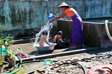 Mandalay, Myanmar - 9 Kasım 2019: Birmanyalı anne çocuklarını suyla yıkıyor