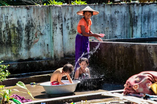Mandalay, Myanmar - 09 Kasım 2019: Birmanyalı anne Mandalay, Myanmar 'da çocuklarını suyla yıkıyor.