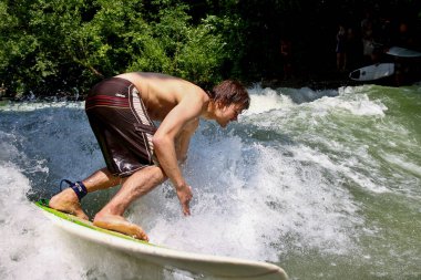 Münih, Almanya - 13 Temmuz 2019: Münih şehir nehrinde sörfçü, Eisbach adı verilen kentsel çevrede sörf yapan insanlarla ünlüdür.