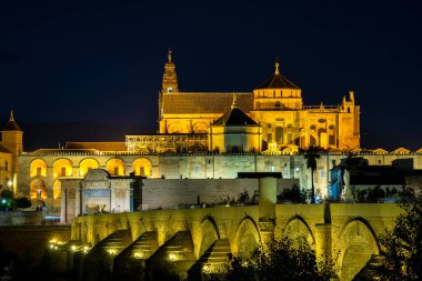 Cordoba, İspanya - 31 Ekim 2019: Mezquita-Katedral ve Puente Romano - Cami-Katedral ve gece İspanya 'nın Endülüs kentindeki Roma Köprüsü
