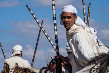 Rabat, Morocco - Oct 13, 2019: Local equestrians participate in a traditional fantasia event or MOUSSEM TBOURIDA in Arabic and wearing a traditional Moroccan dress and accessories clipart