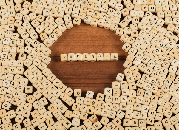 Ανατροφοδότηση γράμματα κύβους σε ένα ξύλινο ταμπλό με — Φωτογραφία Αρχείου