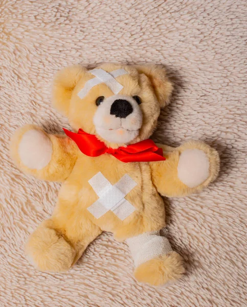 Sick teddy bear lies on a fur blanket