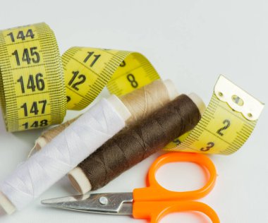 Bir terzide beyaz bir arka plana karşı çeşitli renklerde iplik ruloları dikmek