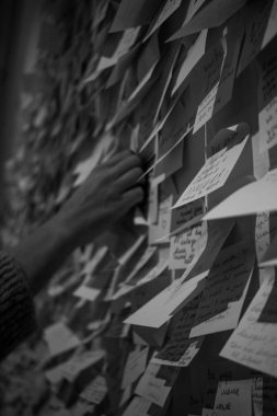 Duvara yapıştırılmış farklı yazı ve çizimlerle yapıştırılmış kağıt çıkartmaları. Notlar için kağıt çıkartmalar. Duvara yapıştırılmış kağıt parçalarıyla yapıştırılmış. Arka plandaki çıkartmalar için. Resim siyah beyaz.