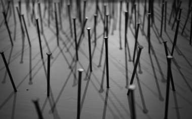 Yapı çivilerinin siyah ve beyaz bir fotoğrafı tuvale sokuluyor ve üzerine gölge düşürülüyor. Yapı çivilerinin makro fotoğrafçılığı beyaz arka plan çivilerine siyah inşaat çivileri çakmak beyaz arka plan üzerine bir arka plan oluşturur. beyaz boya