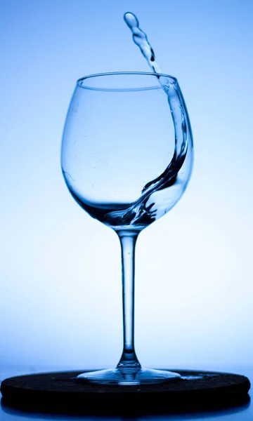 a splash of liquid in a glass wine glass. water pouring inside a glass wine glass. a curl of water in a wine glass. drink in a glass wine glass .splash in the glass