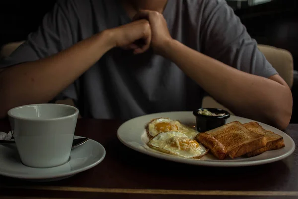 Gri tişörtlü kız omlet ve kızarmış sosis yiyor.