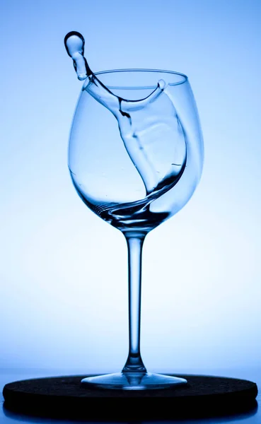 Cam şarap kadehinde bir damla sıvı. Cam bir şarap kadehinin içine su dökülüyor. Şarap kadehinde bir bukle su. Bardakta içki. Bardakta su sıçradı.