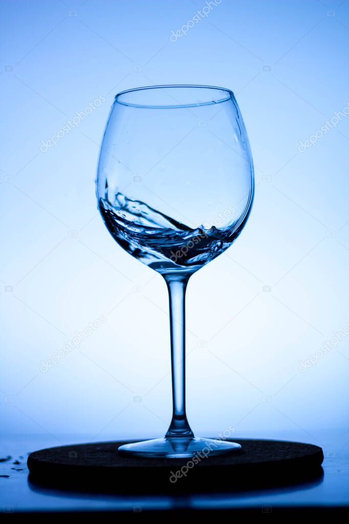 a splash of liquid in a glass wine glass. water pouring inside a glass wine glass. a curl of water in a wine glass. drink in a glass wine glass .splash in the glass