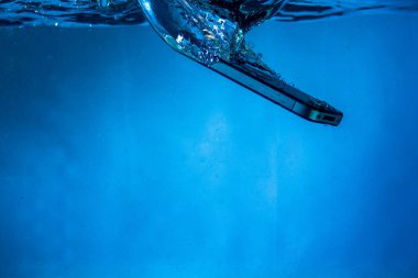 Siyah beyaz telefon suya düştü. Telefonun suda. Mavi su. Telefon su kabarcıklarında. Telefon suya batıyor.