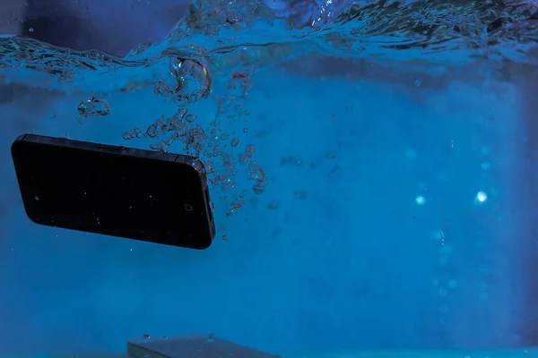 Siyah beyaz telefon suya düştü. Telefonun suda. Mavi su. Telefon su kabarcıklarında. Telefon suya batıyor.