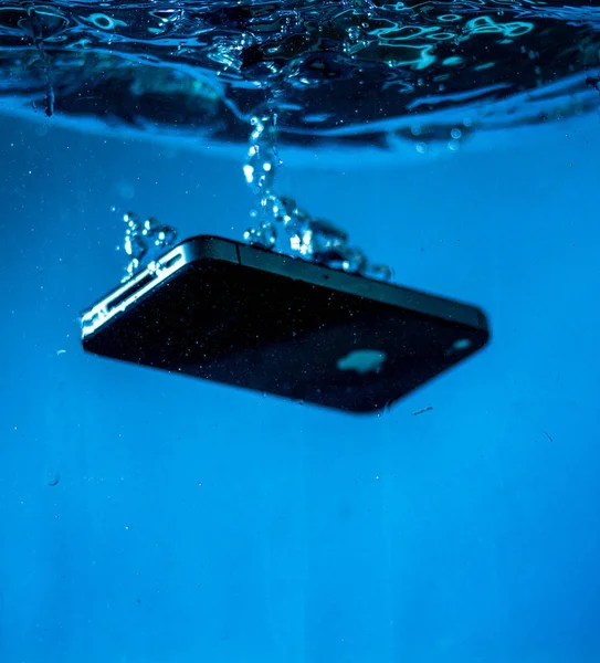 Siyah beyaz telefon suya düştü. Telefonun suda. Mavi su. Telefon su kabarcıklarında. Telefon suya batıyor.