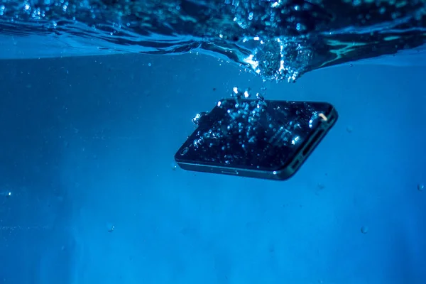 Siyah beyaz telefon suya düştü. Telefonun suda. Mavi su. Telefon su kabarcıklarında. Telefon suya batıyor.