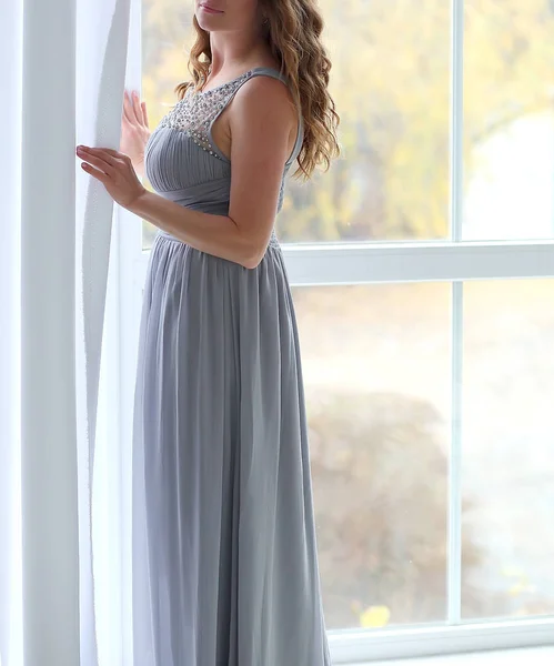 Νεαρή γυναίκα με φόρεμα που βρίσκεται κοντά στα παράθυρα — Φωτογραφία Αρχείου