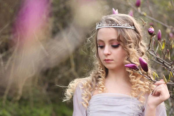 Jovem menina bonita em um vestido lilás leve no jardim onde — Fotografia de Stock