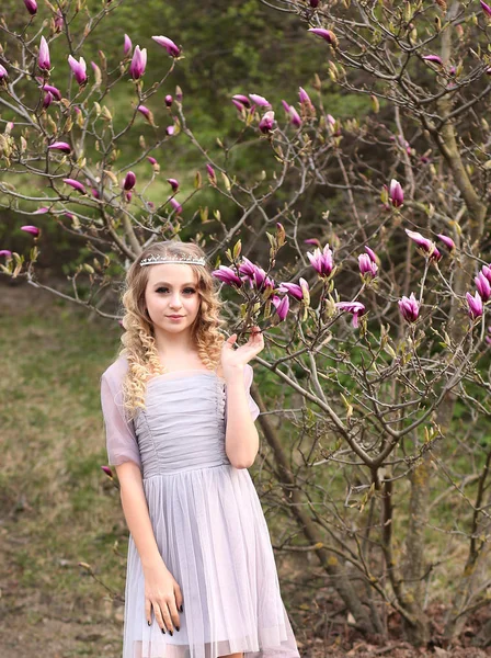 Jovem menina bonita em um vestido lilás leve no jardim onde — Fotografia de Stock