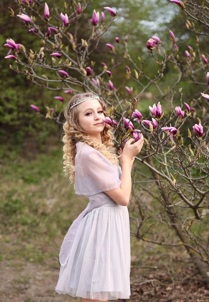 Fiatal gyönyörű lány egy könnyű orgona ruha a kertben, ahol — Stock Fotó