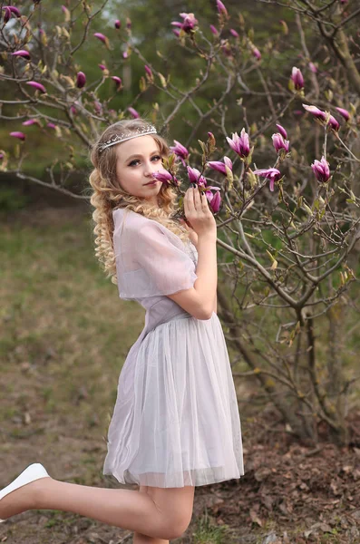 Jong mooi meisje in een licht lila jurk in de tuin waar — Stockfoto