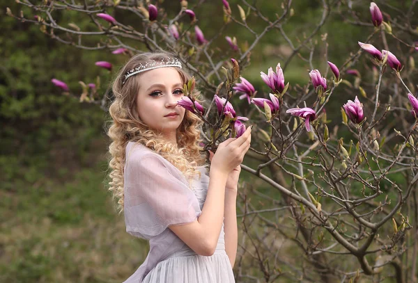 Joven hermosa chica en un vestido lila luz en el jardín donde — Foto de Stock