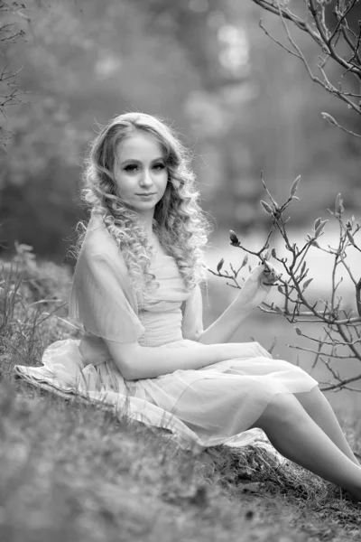 Ung vacker flicka i en ljus syren klänning i trädgården där — Stockfoto