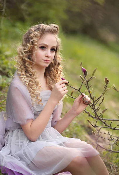 Jovem menina bonita em um vestido lilás leve no jardim onde — Fotografia de Stock