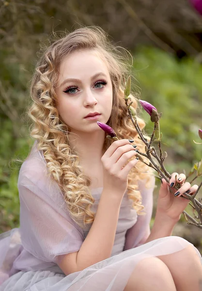 Jeune belle fille dans une robe lilas clair dans le jardin où — Photo