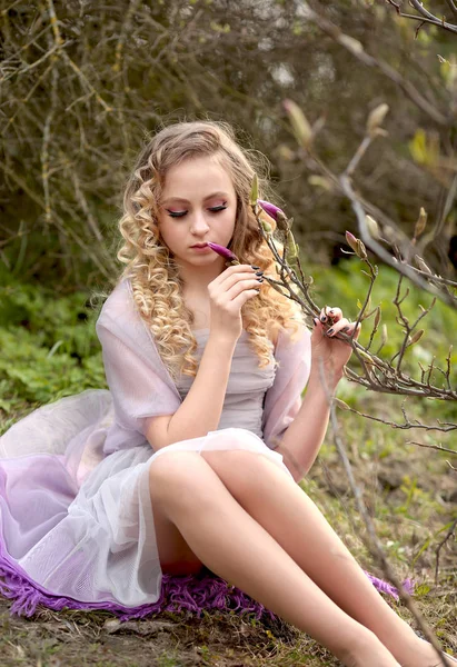 Jeune belle fille dans une robe lilas clair dans le jardin où — Photo