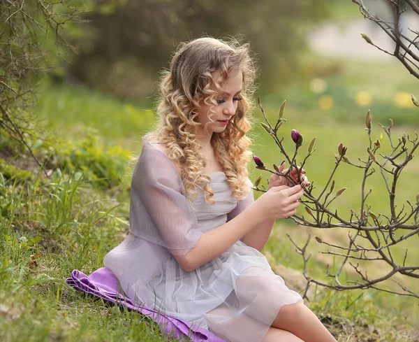 Młoda piękna dziewczyna w lekkiej sukience liliowej w ogrodzie, gdzie — Zdjęcie stockowe