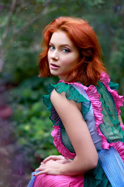 Bela menina ruiva em arranjador onde azálea floresce em um vestido de voo colorido — Fotografia de Stock