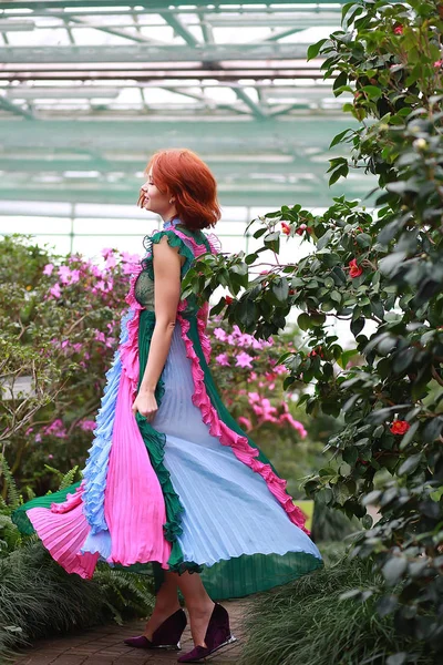 Schöne rothaarige Mädchen in Arrangeur, wo Azaleen in einem bunten fliegenden Kleid blüht — Stockfoto