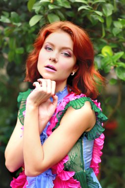 Renkli bir elbiseyle açelyanın açtığı aranjördeki güzel kızıl saçlı kız.