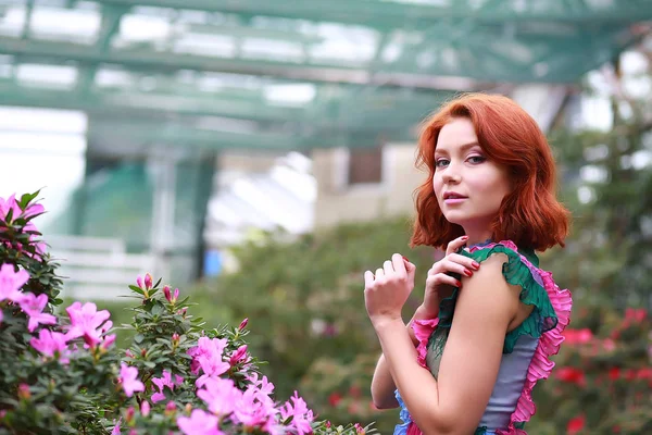 Hermosa chica pelirroja en arreglista donde azalea florece en un vestido volador colorido —  Fotos de Stock