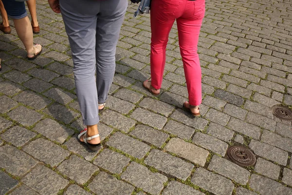 Turisté v kalhotách a teniskách procházejí náměstí — Stock fotografie