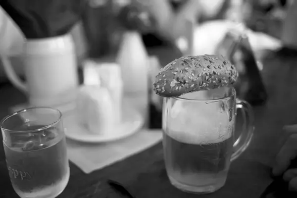 Um pão de gergelim jaz em cima de uma cerveja em um pub — Fotografia de Stock